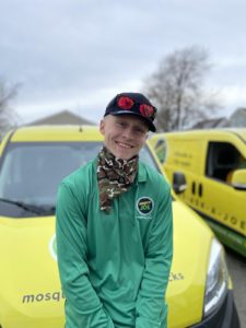 Technician in a green long-sleeved shirt poses for a picture while leaning against a service van.